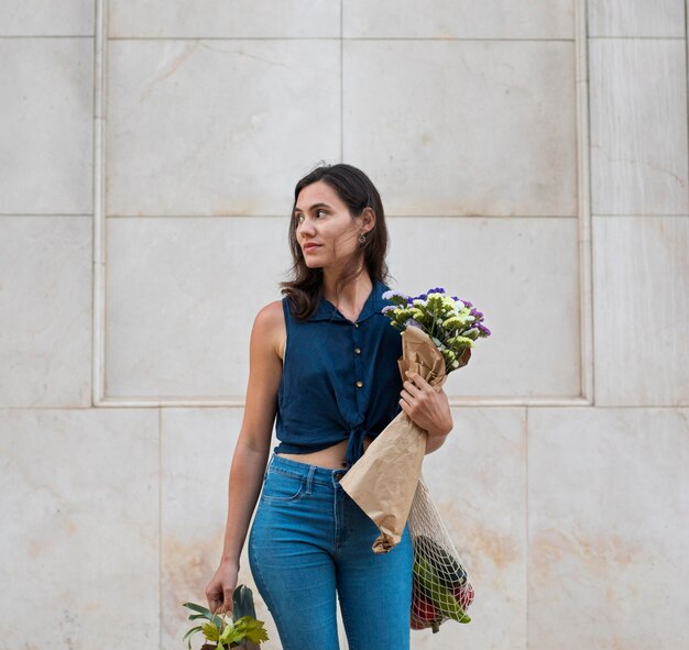 Medium shot woman carrying bags and flowers