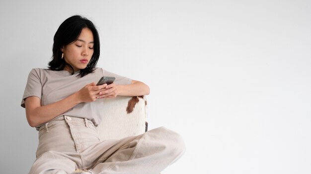 Medium shot woman on chair with smartphone