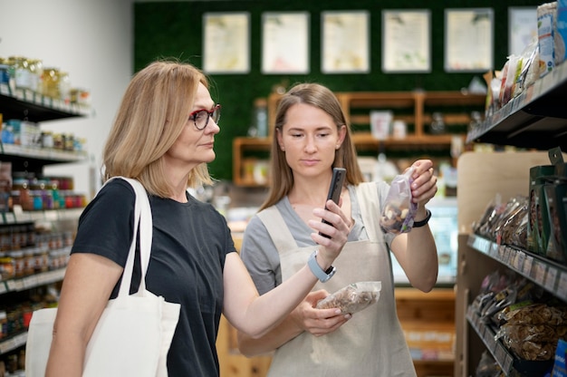 Free photo medium shot woman checking product with phone