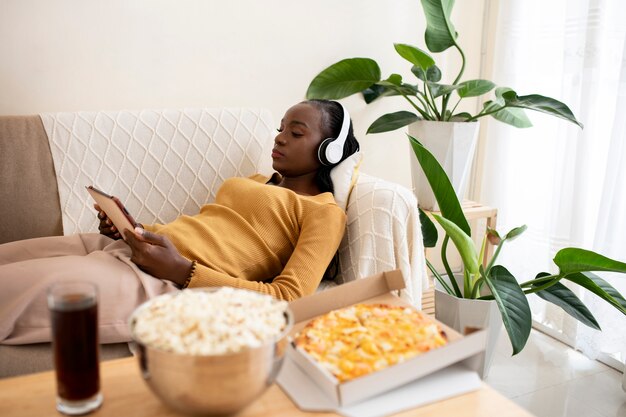 Medium shot woman on couch with tablet