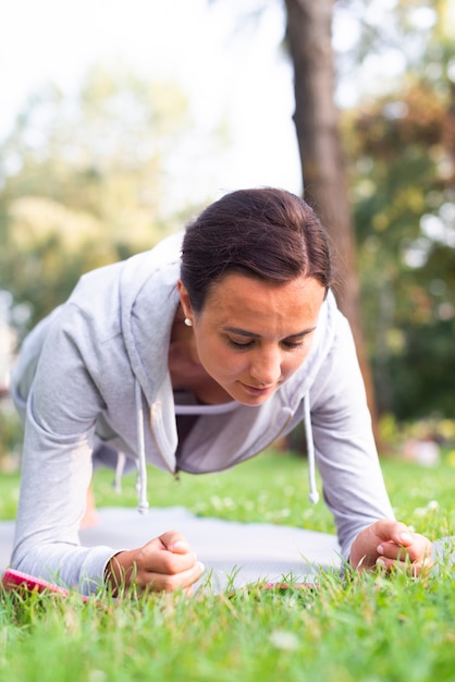 Free Photo medium shot woman doing planks outdoors