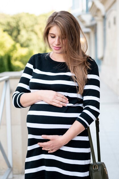 Medium shot woman in dress holding belly