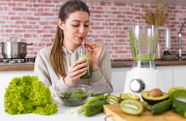 Free photo medium shot woman drinking green smoothie