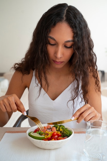 Medium shot woman eating salmon bowl