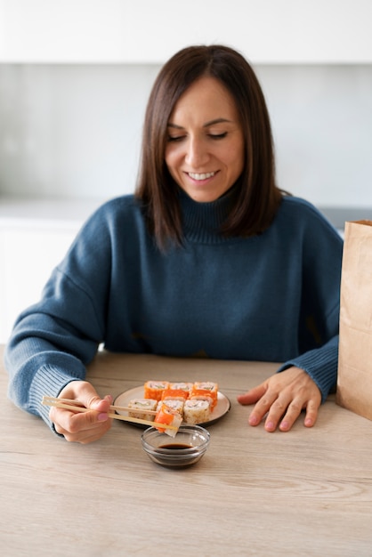 Medium shot woman eating sushi at home