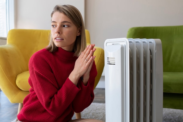 Free photo medium shot woman getting warm near heater