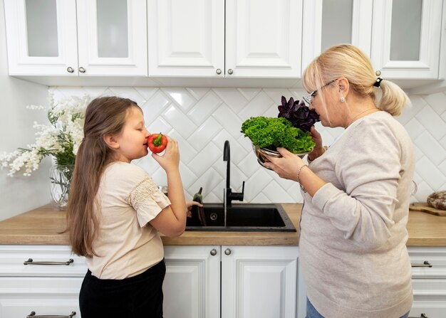 Medium shot woman and girl smelling vegetables