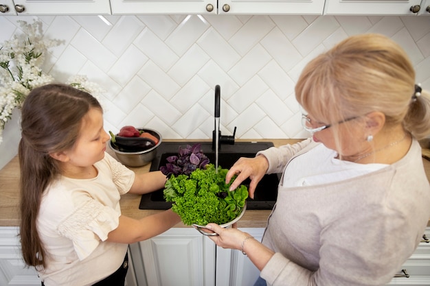 Medium shot woman and girl with lettuce