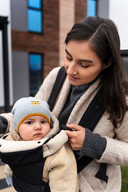 Free photo medium shot woman holding baby in carrier