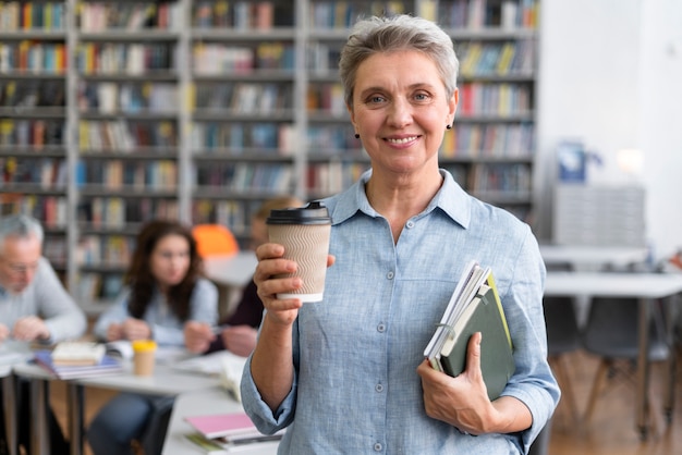 Free photo medium shot woman holding books and cup