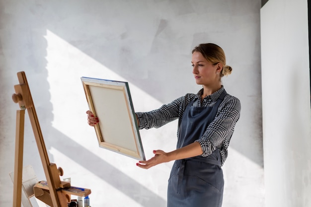 Free Photo medium shot of woman holding canvas in studio