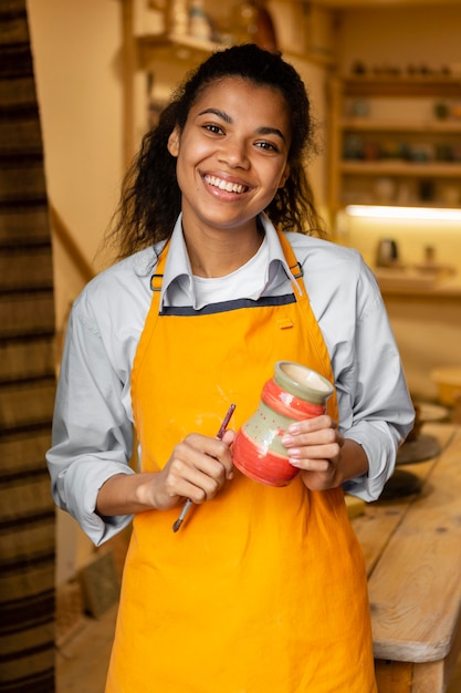 Free photo medium shot woman holding clay pot