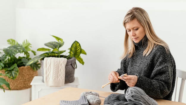 Medium shot woman holding knitting needles