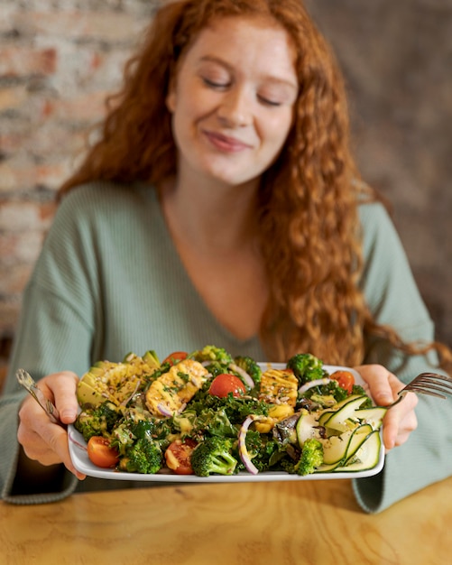 Free photo medium shot woman holding plate with food