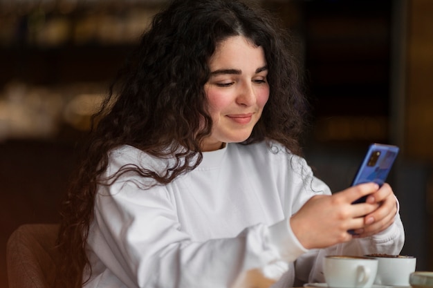 Medium shot woman holding smartphone