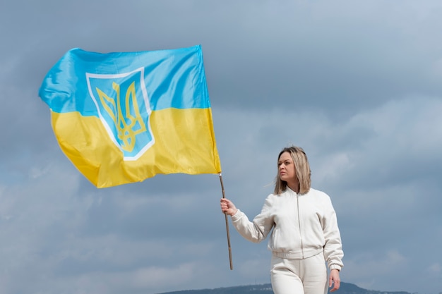 Medium shot woman holding ukranian flag outdoors