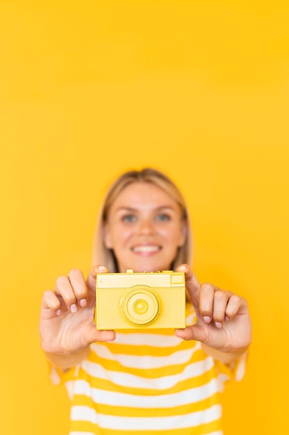 Free photo medium shot woman holding yellow camera