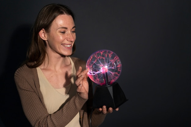 Medium shot woman interacting with a plasma ball