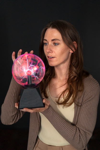 Free photo medium shot woman interacting with a plasma ball