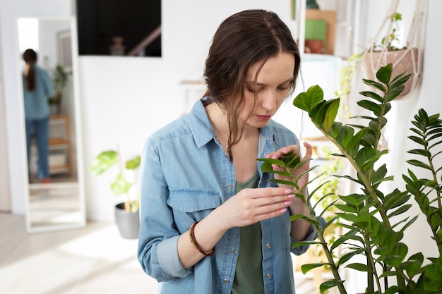 Medium shot woman looking at plant