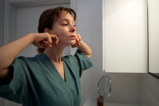 Medium shot woman massaging face at home