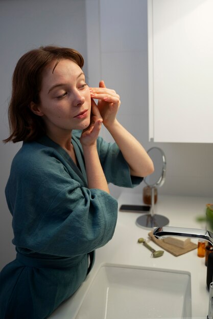 Medium shot woman massaging face at home