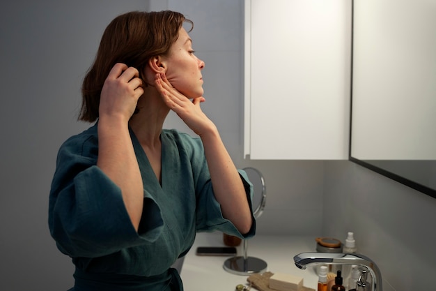 Medium shot woman massaging face at home