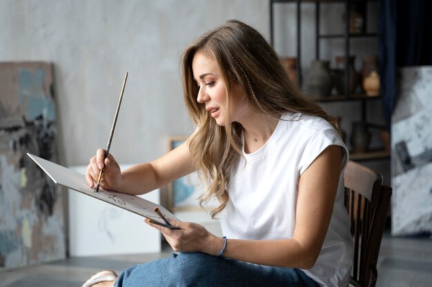 Medium shot woman painting on canvas