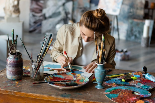 Medium shot woman painting on desk