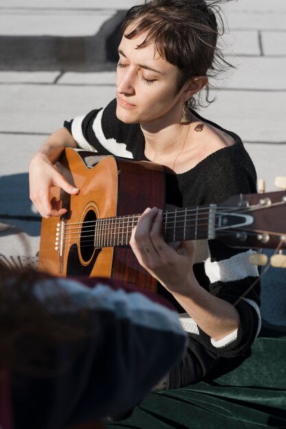 Medium shot woman playing the guitar