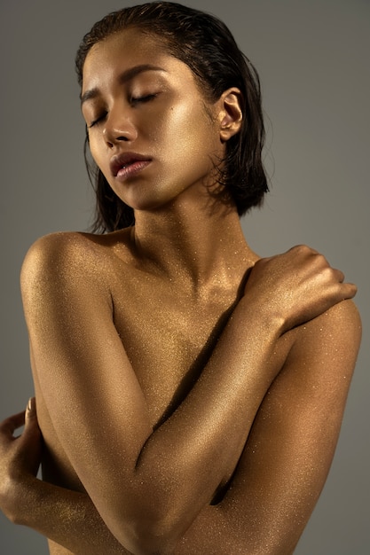 Medium shot woman posing with gold body painting