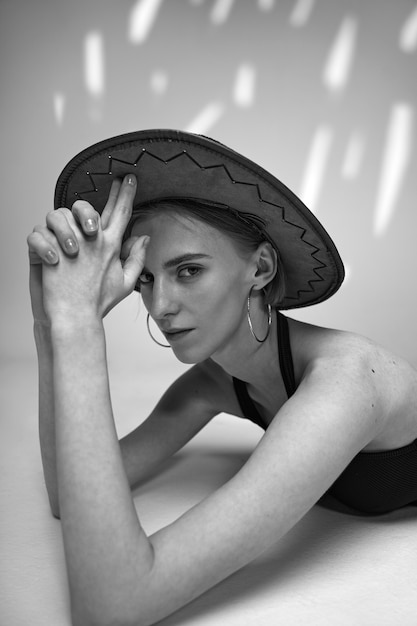 Free photo medium shot woman posing with hat black and white