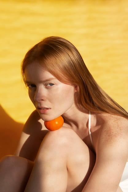 Medium shot woman posing with tangerine