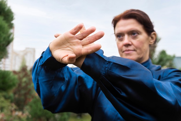 Free photo medium shot woman practicing tai chi outdoors