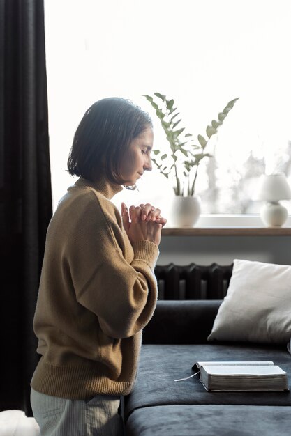 Medium shot woman praying in living room