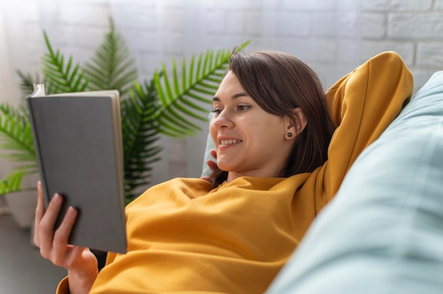 Free photo medium shot woman reading on couch