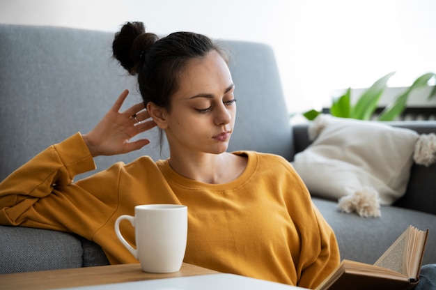 Medium shot woman reading in living room