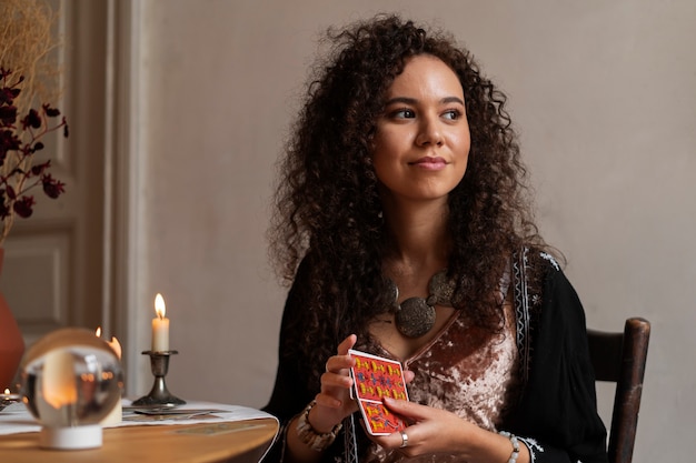 Medium shot woman reading tarot at table