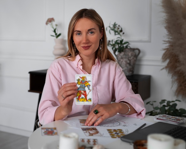 Medium shot woman reading tarot with laptop