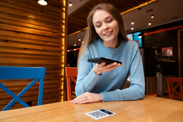 Medium shot woman scanning qr at restaurant