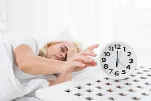 Free photo medium shot woman sleeping with clock