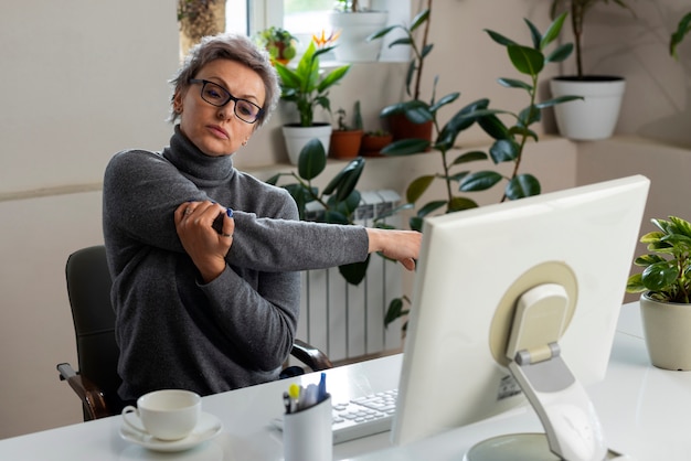 Free photo medium shot woman stretching at desk