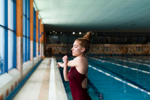 Medium shot woman in swimsuit stretching