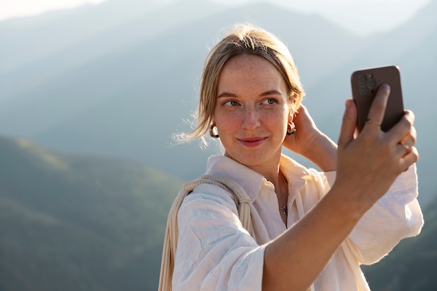 Medium shot woman taking selfie on mountain