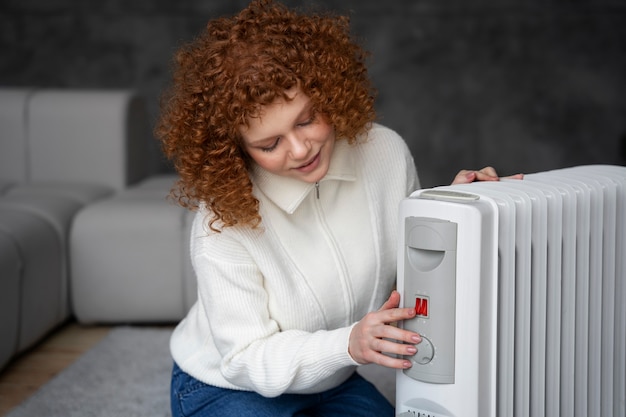 Free photo medium shot woman turning on the heater