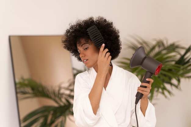 Medium shot woman using blow dryer