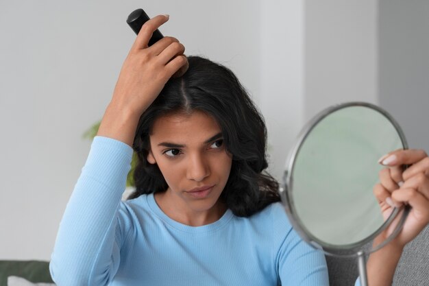 Medium shot woman using dry shampoo at home