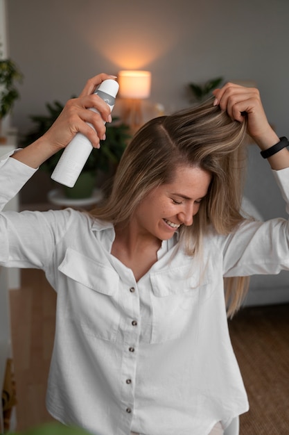 Medium shot woman using dry shampoo at home