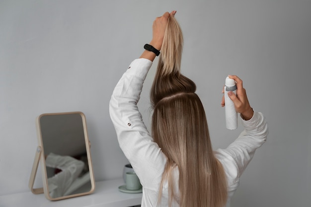 Medium shot woman using dry shampoo at home