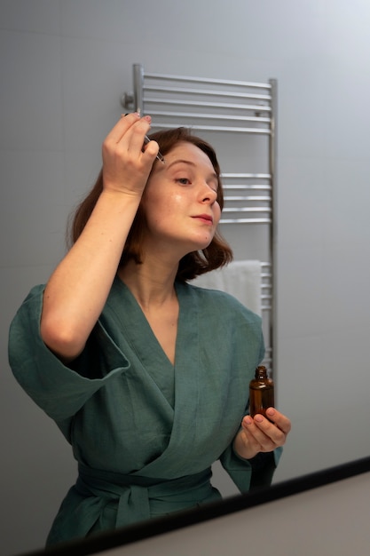 Medium shot woman using face serum